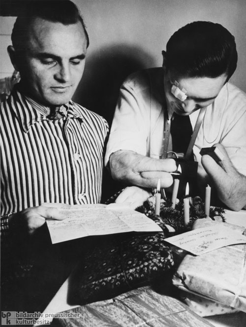 Ein Kriegsversehrter „Ohnhänder” zündet Adventskerzen an (Dezember 1949)